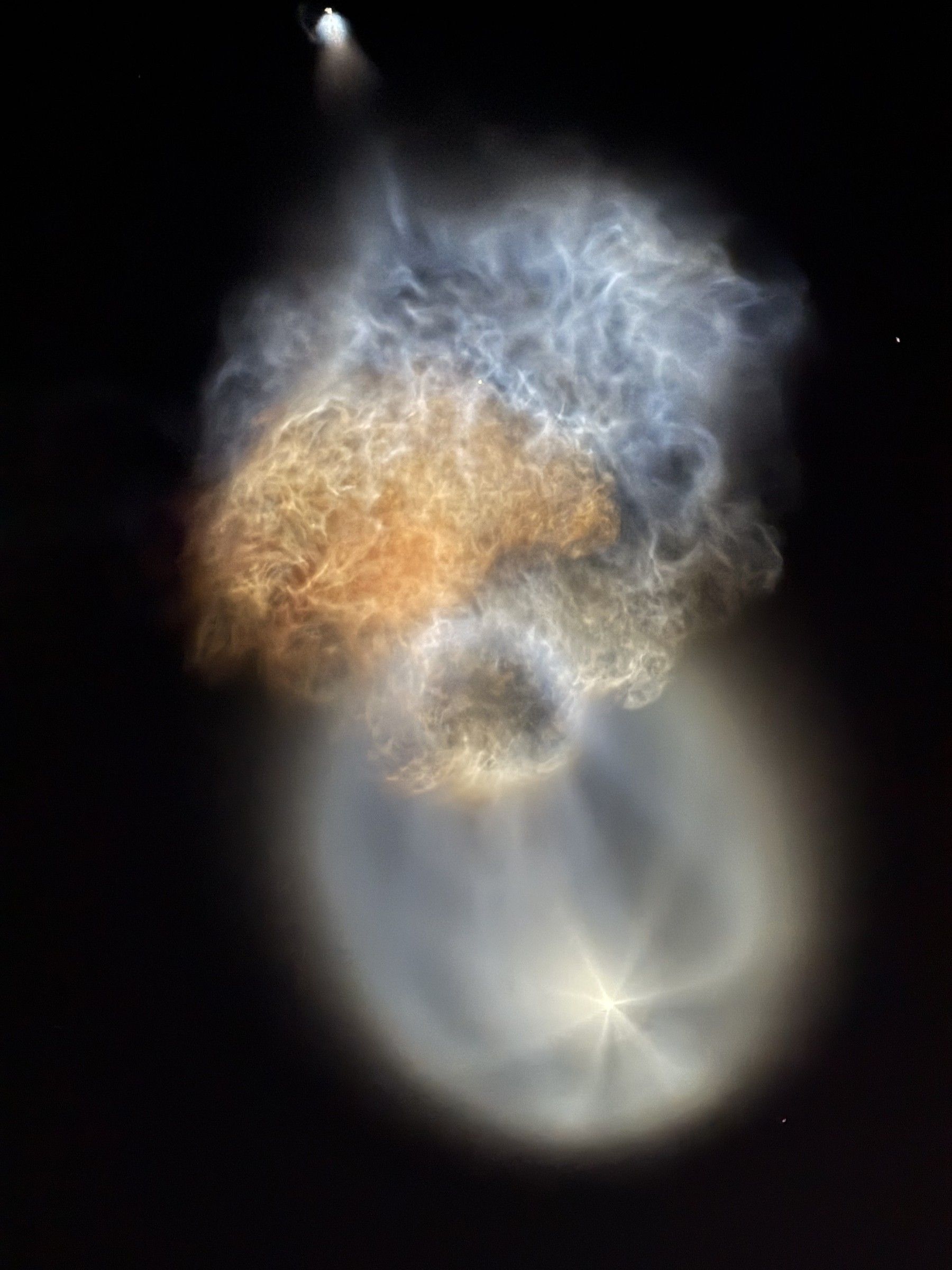 Glowing, rippled rocket exhaust plume with an orange band and a pale oval shell, against a dark sky
