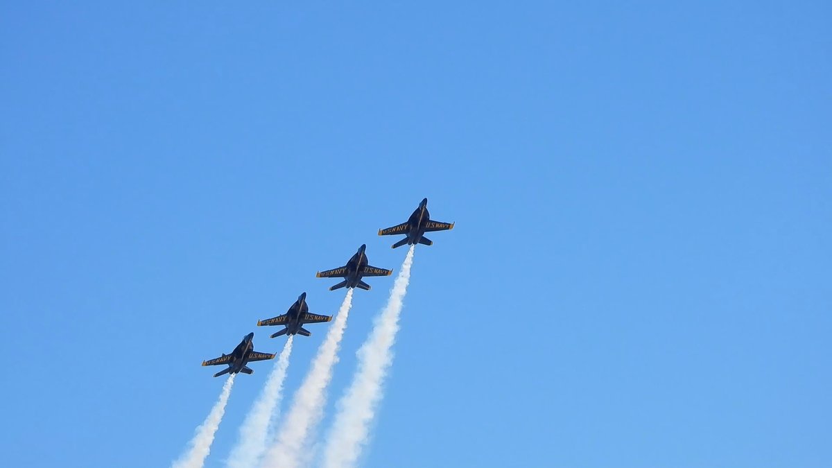 Four jets climb in a staggered line, each trailing a white smoke plume