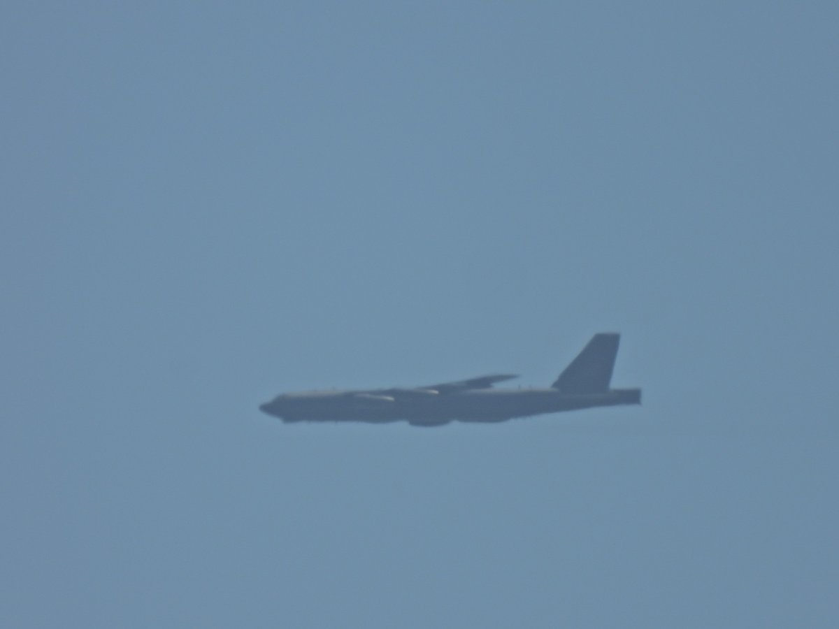 The long side profile of a B-52 bomber in level flight in hazy sky